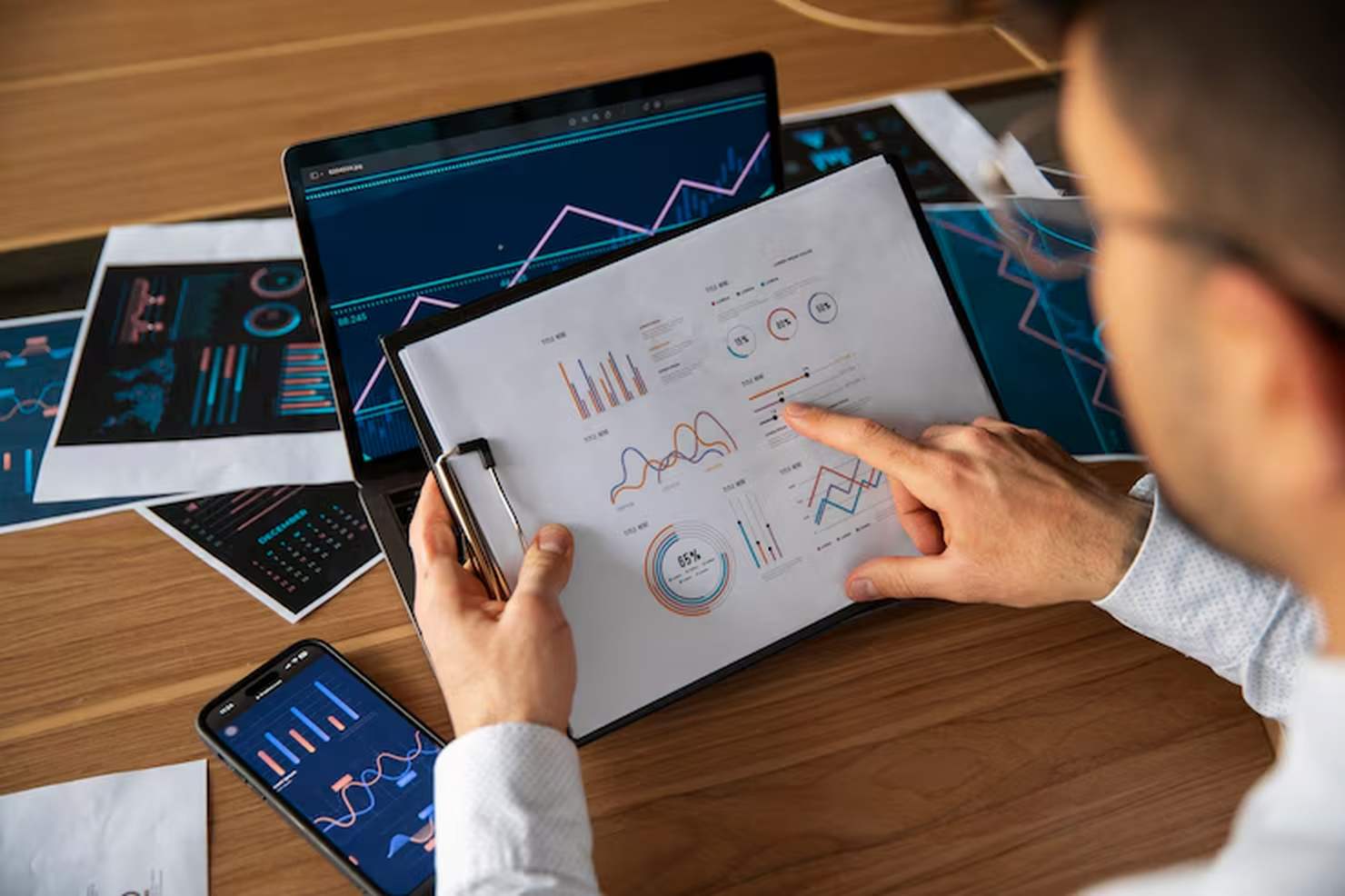 Financial analyst reviewing performance charts on paper and digital screens, illustrating the complexity and data-driven nature of cross-border investment strategies between markets.